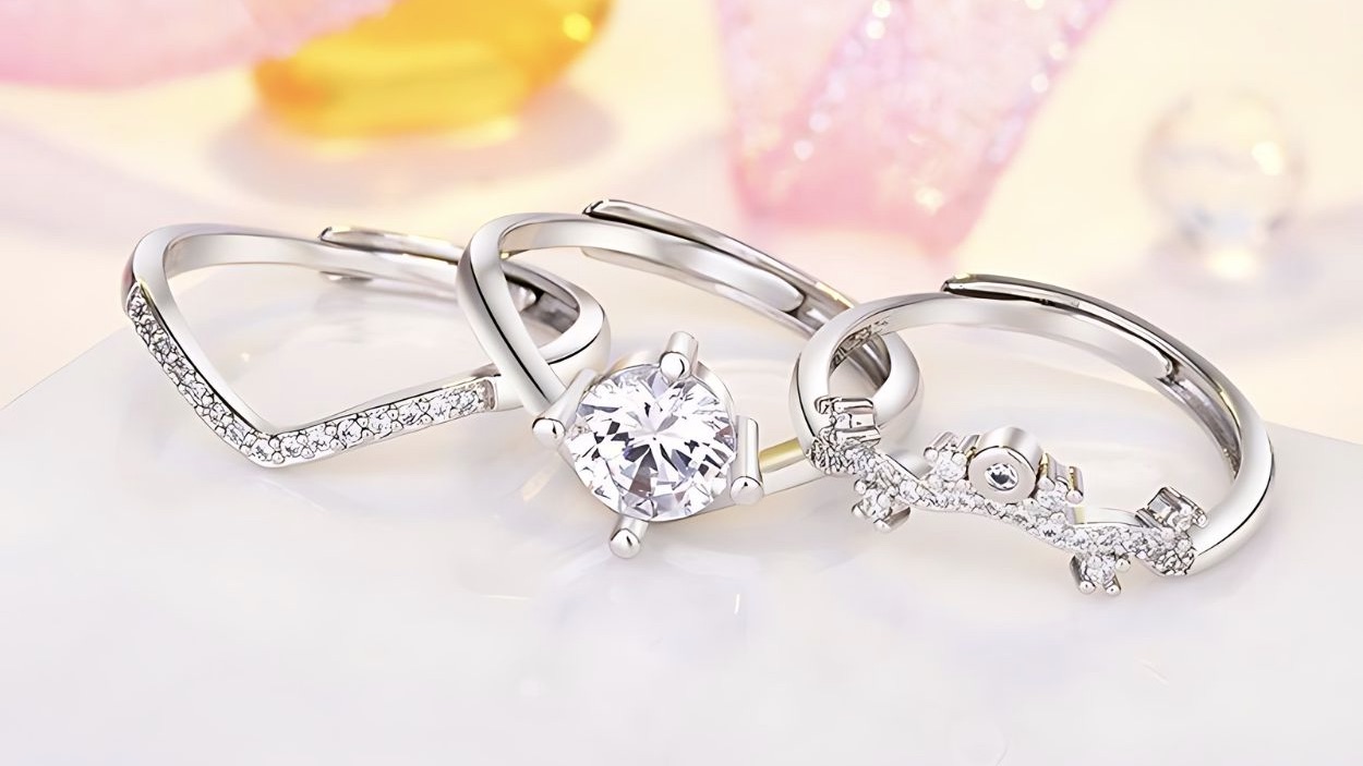 Silver rings with clear stones on a soft pink surface